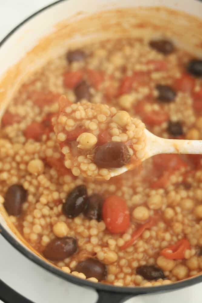 a spoon scooping up a serving of one pot Greek couscous