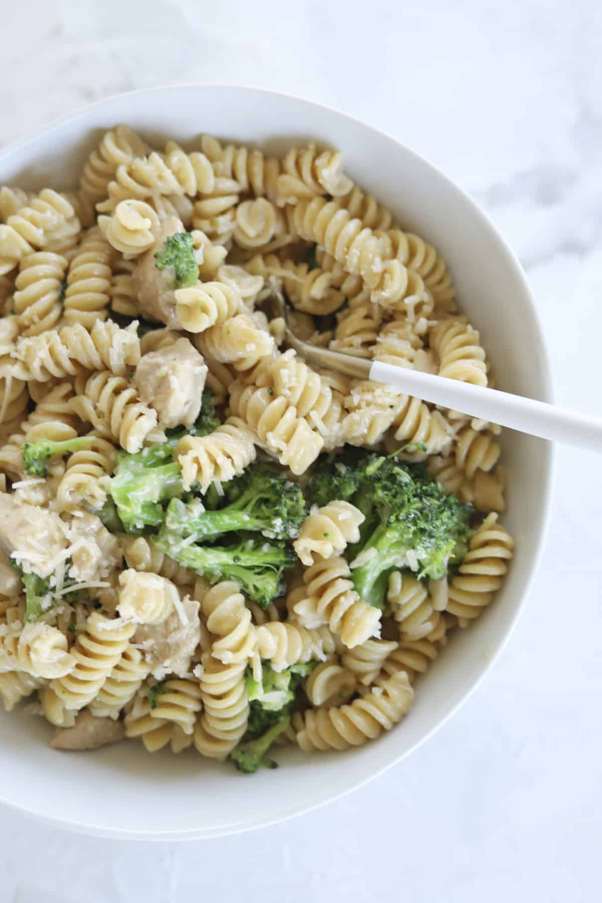 bowl of rotini and broccoli with a spoon sticking out