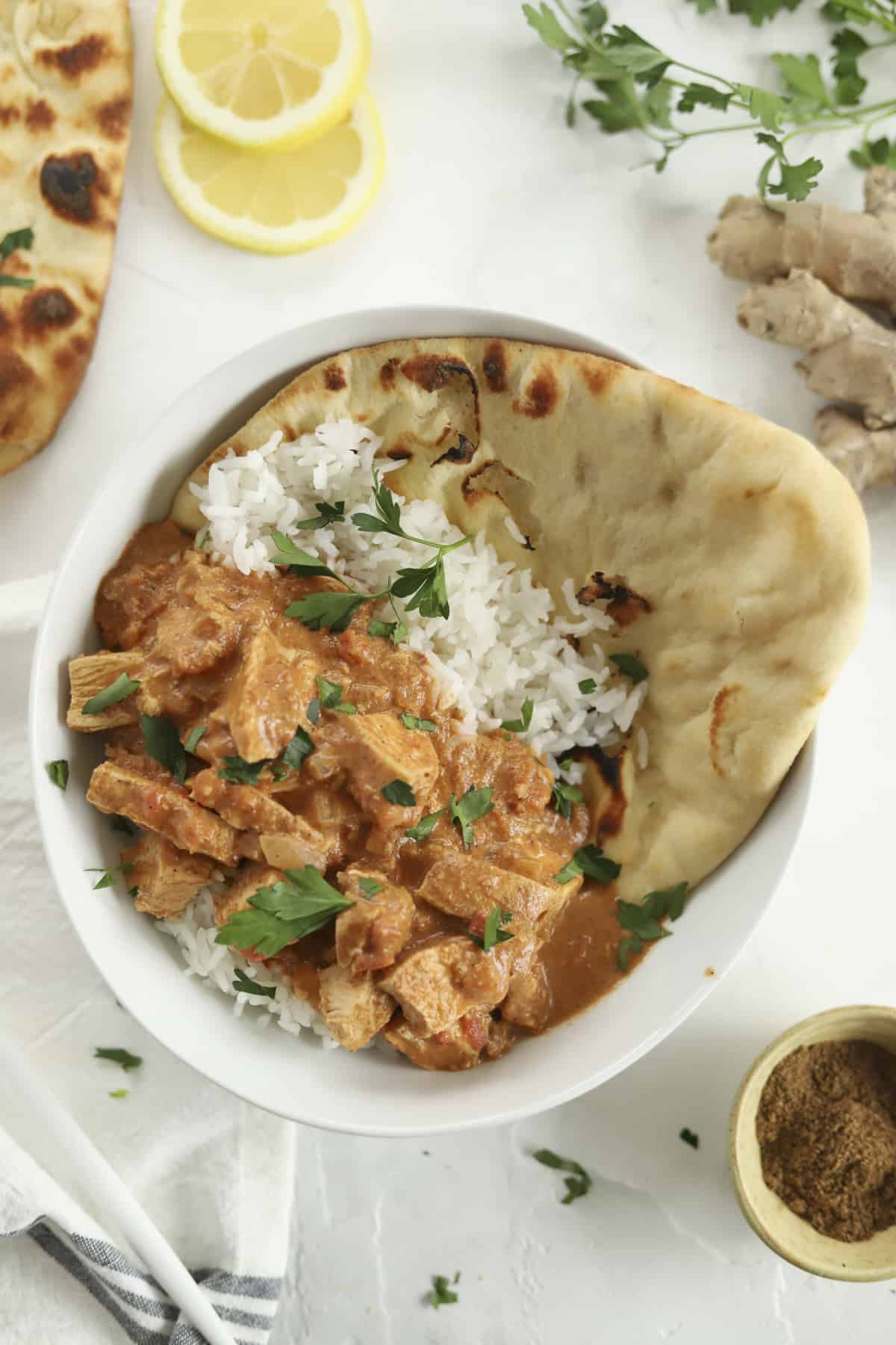 chicken tikka masala over a bed of rice with naan on the side.