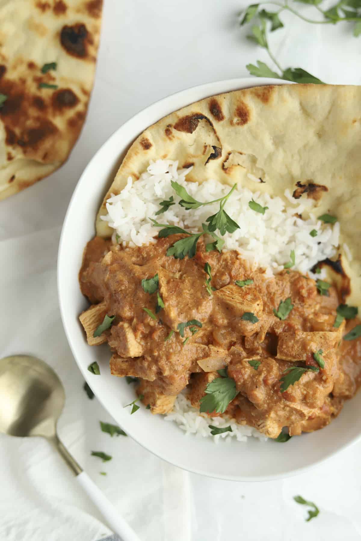 a bowl of chicken tikka masala over rice with naan on the side.