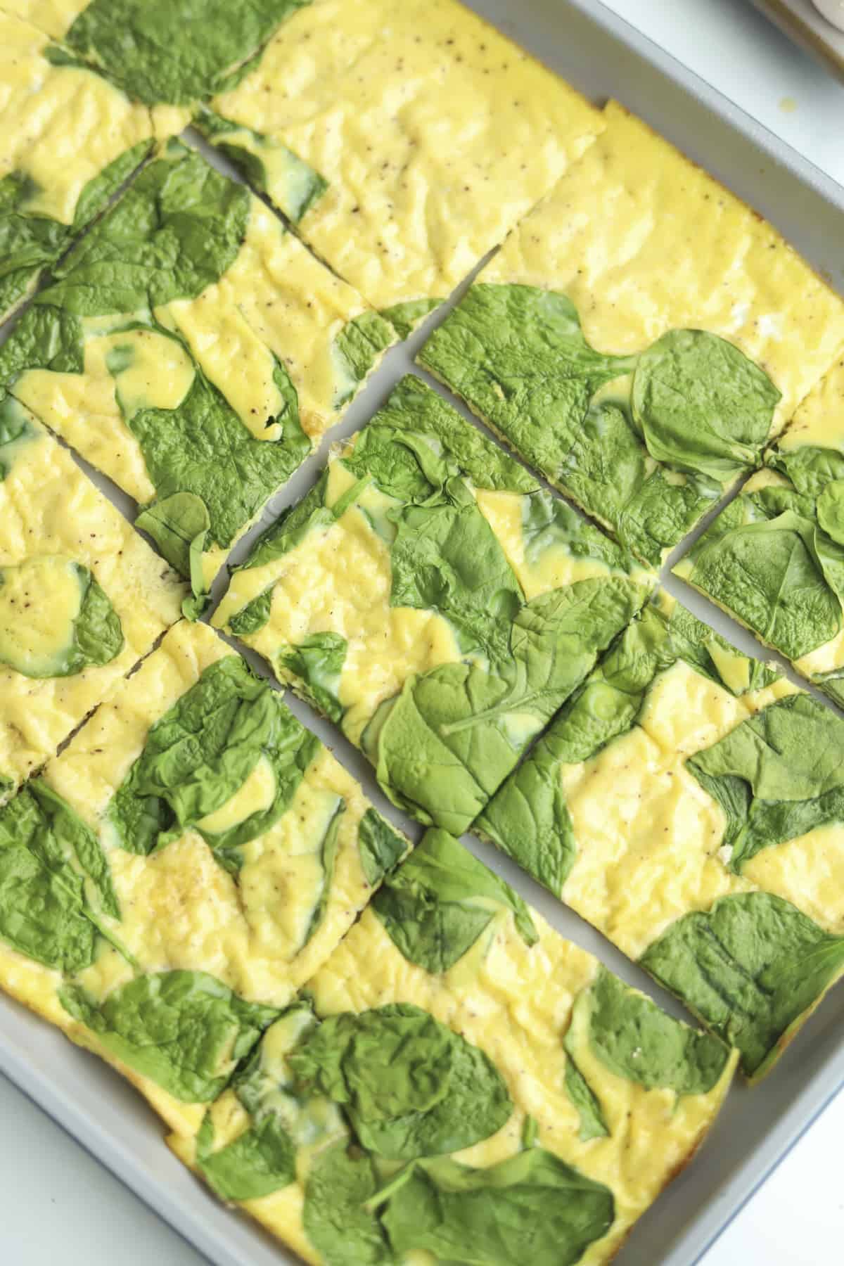 squares of baked eggs and spinach on a pan 