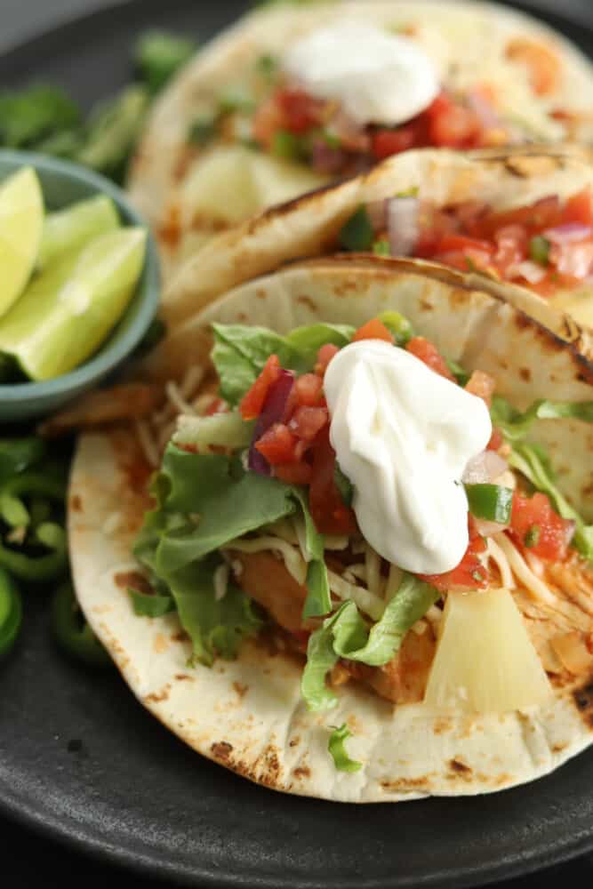 tacos with crockpot chicken fajita fillings topped with sour cream