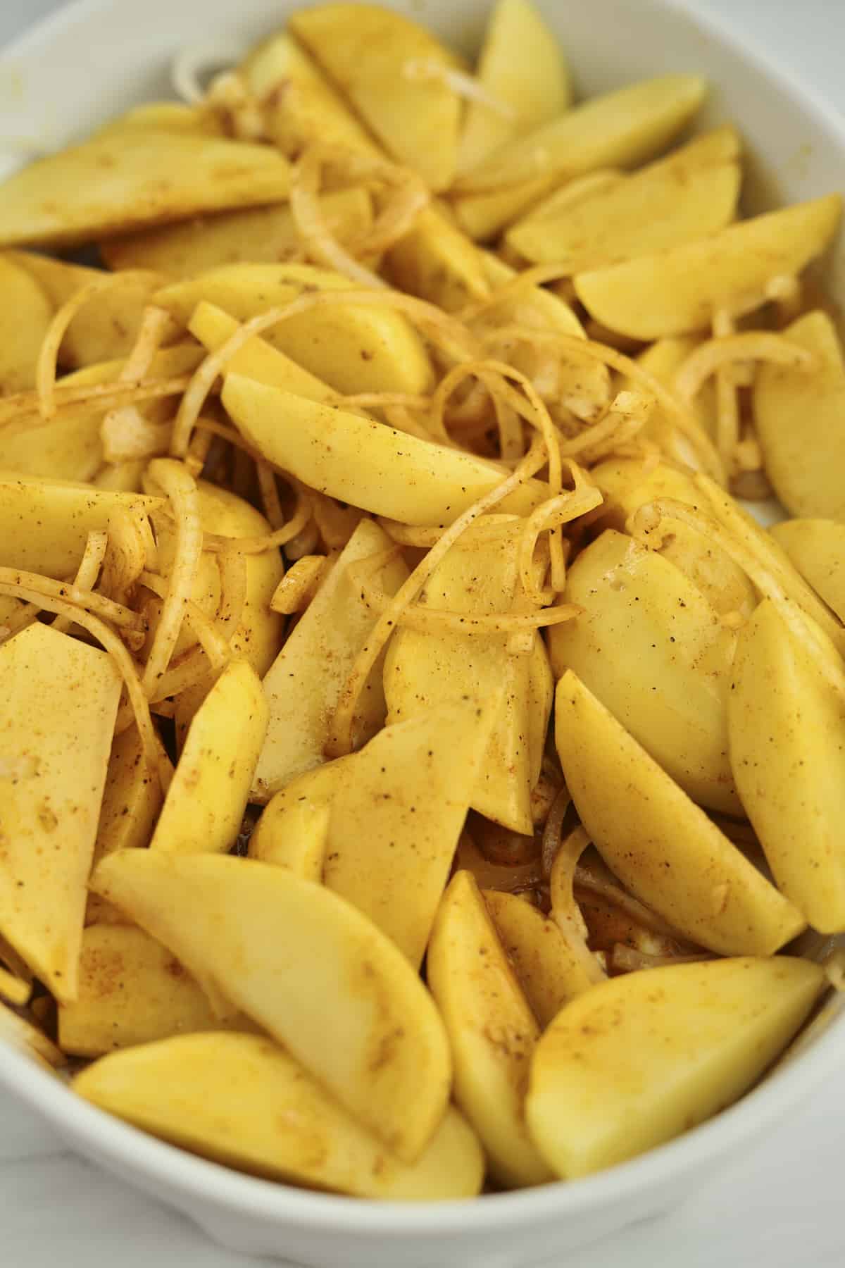 raw potatoes and onions in a baking dish