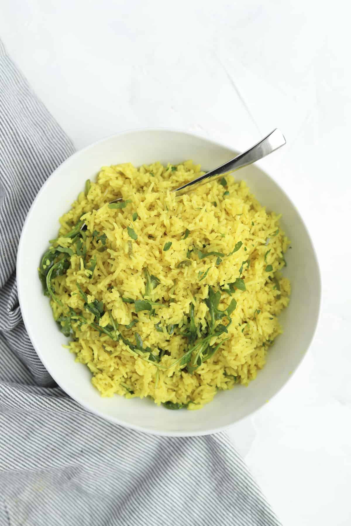 a bowl of coconut turmeric rice topped with fresh herbs