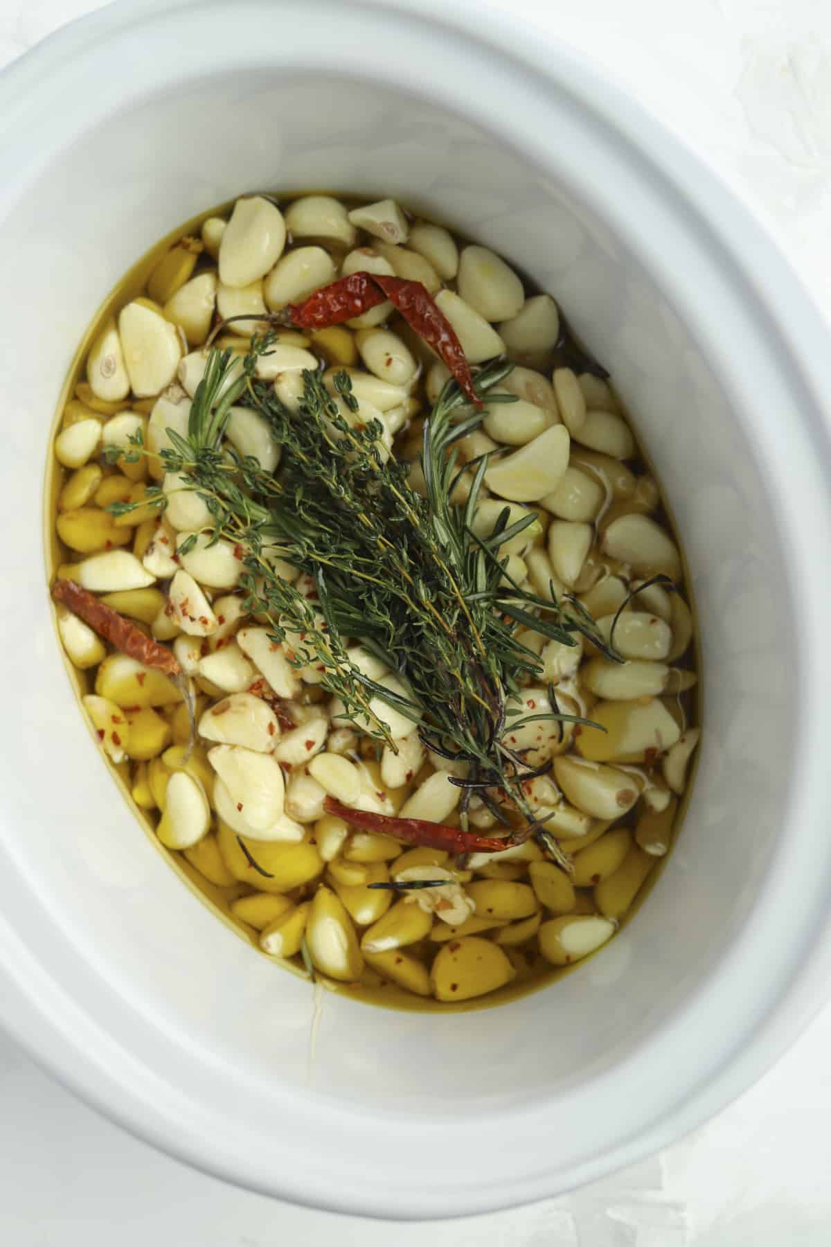 overhead slow cooker garlic confit with fresh herbs