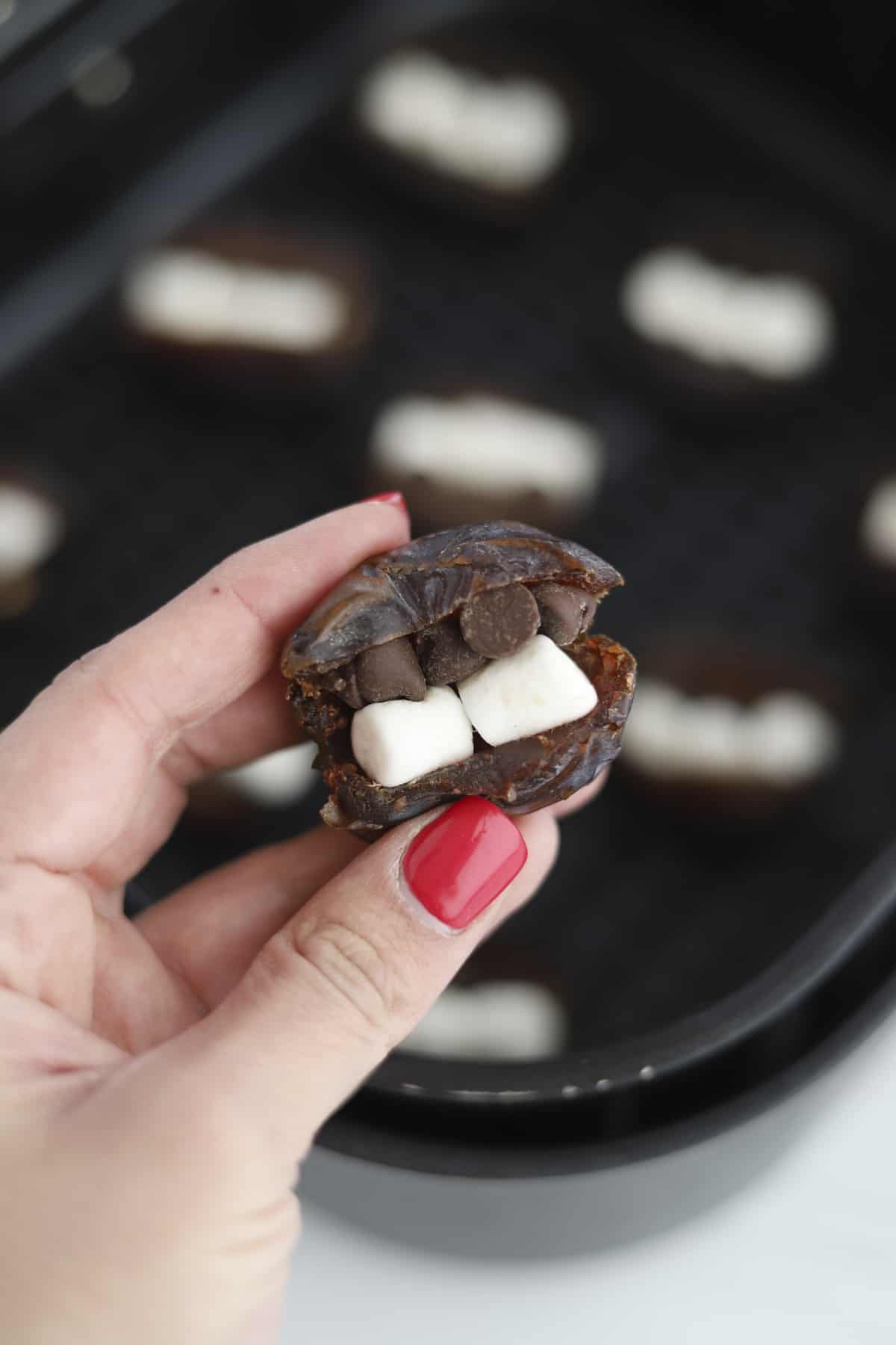 a hand holding s'mores stuffed dates