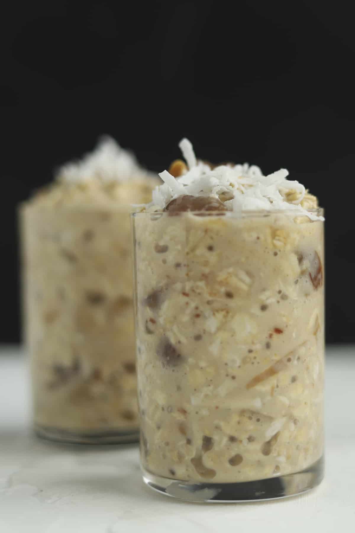two jars of dates & apricots overnight oats topped with shredded coconut flakes