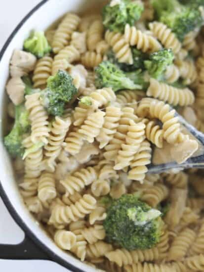 a spoon scooping up a bite from a pot of chicken broccoli rotini