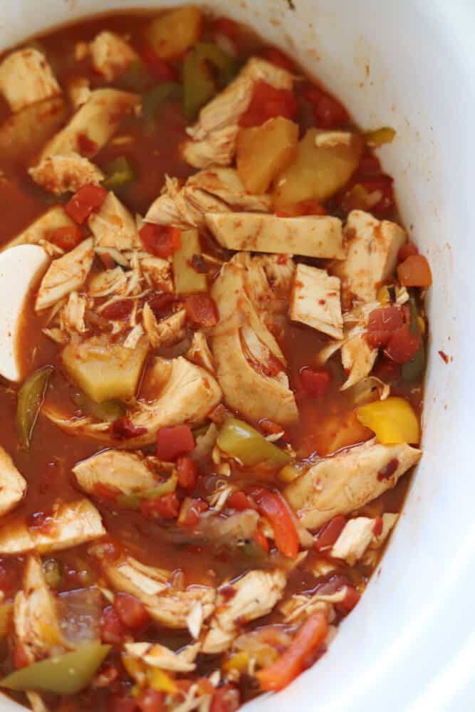 close up image of cooked crock pot chicken fajitas iwth peppers, onions, and pineapple in a crock pot