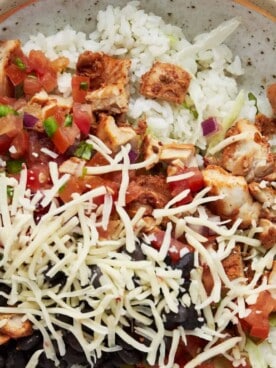 homemade chipotle bowl with chicken topped with cheese and black beans