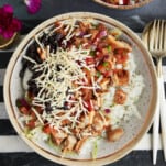 a homemade chipotle bowl with rice, chicken, lettuce, salsa, black beans, and cheese