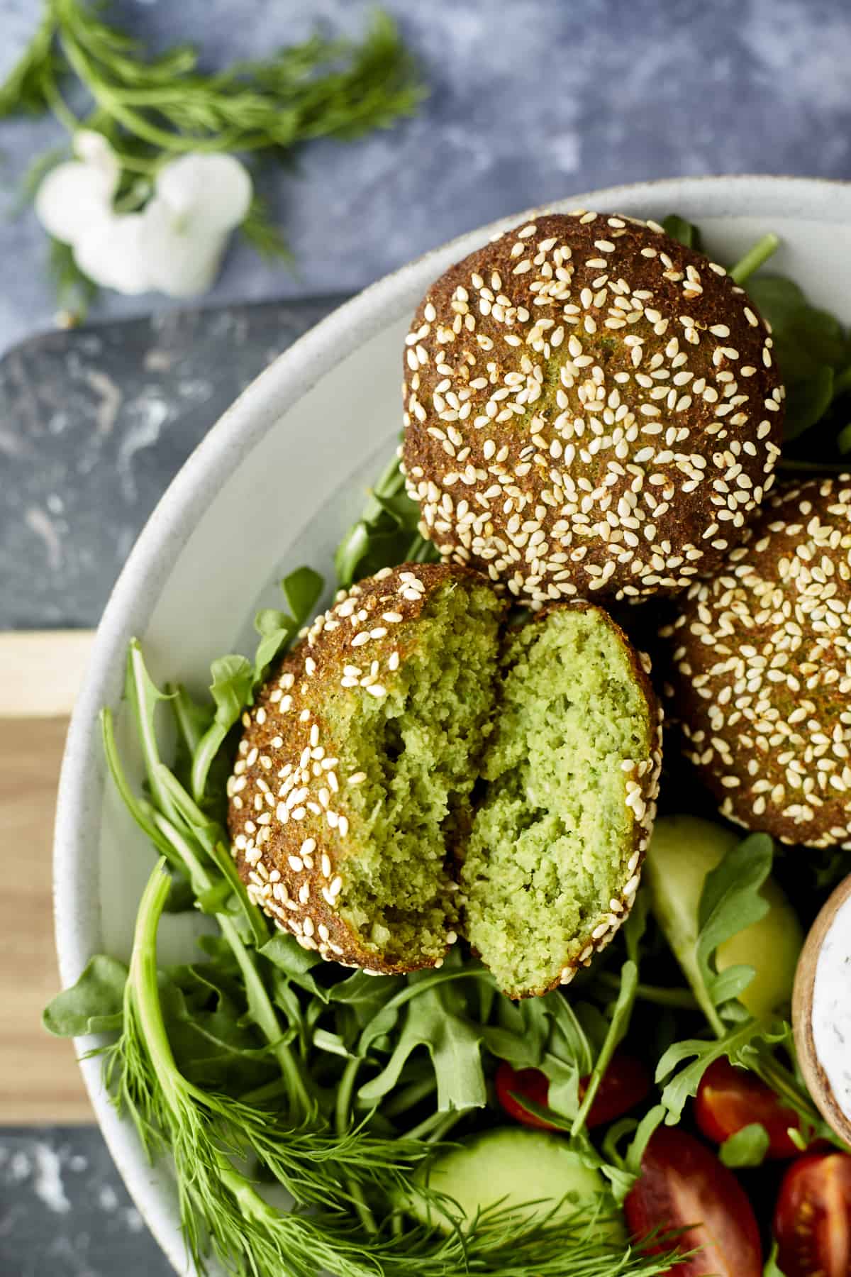 a bowl of falafel with one broken in half 
