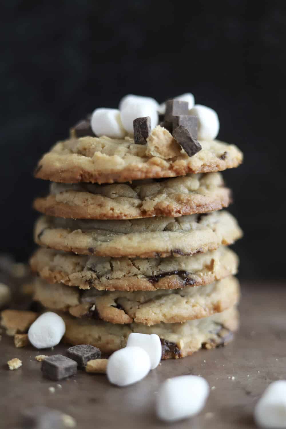 a stack of 6 s'mores cookies with chocolate chunks and marshmallows on top of them and around