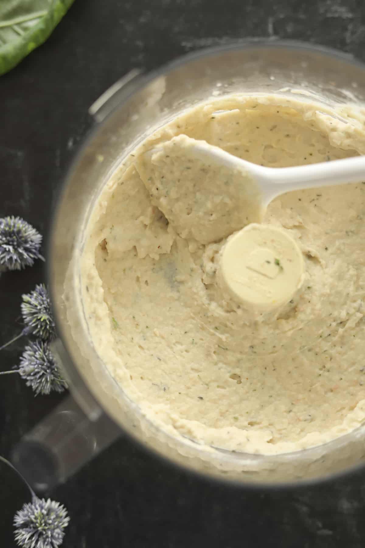 Food processor full of smooth white bean dip. 