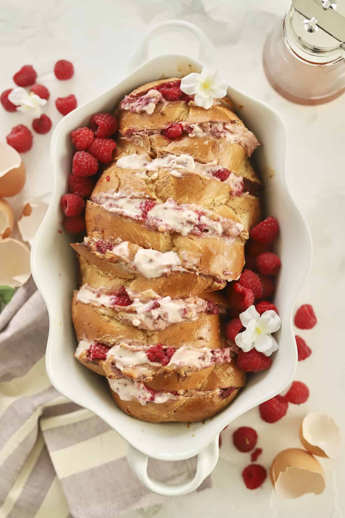overhead image of challah bread stuffed with raspberry cream cheese and fresh raspberries in a baking dish