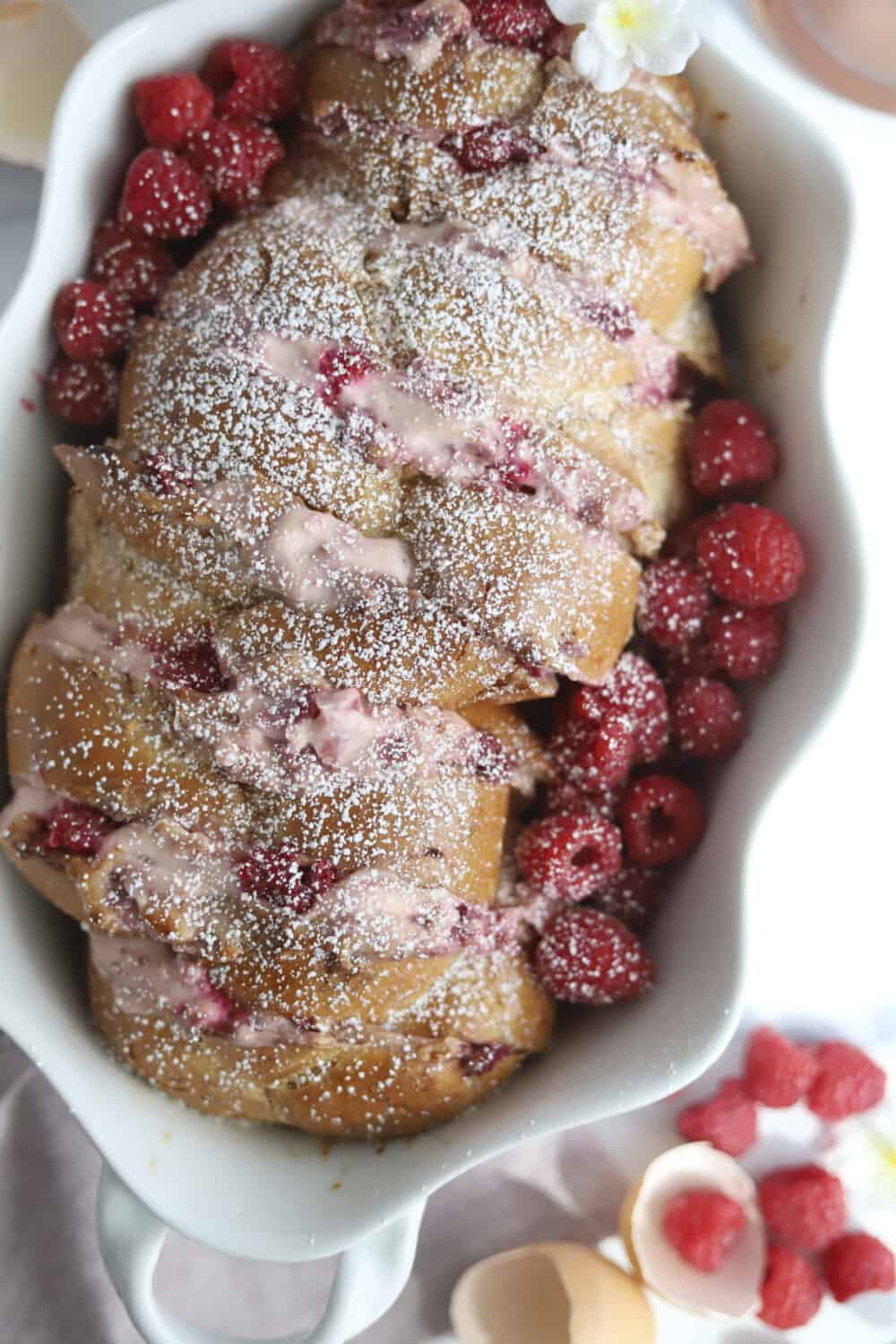 raspberry french toast in a baking dish with fresh raspberries and powdered sugar