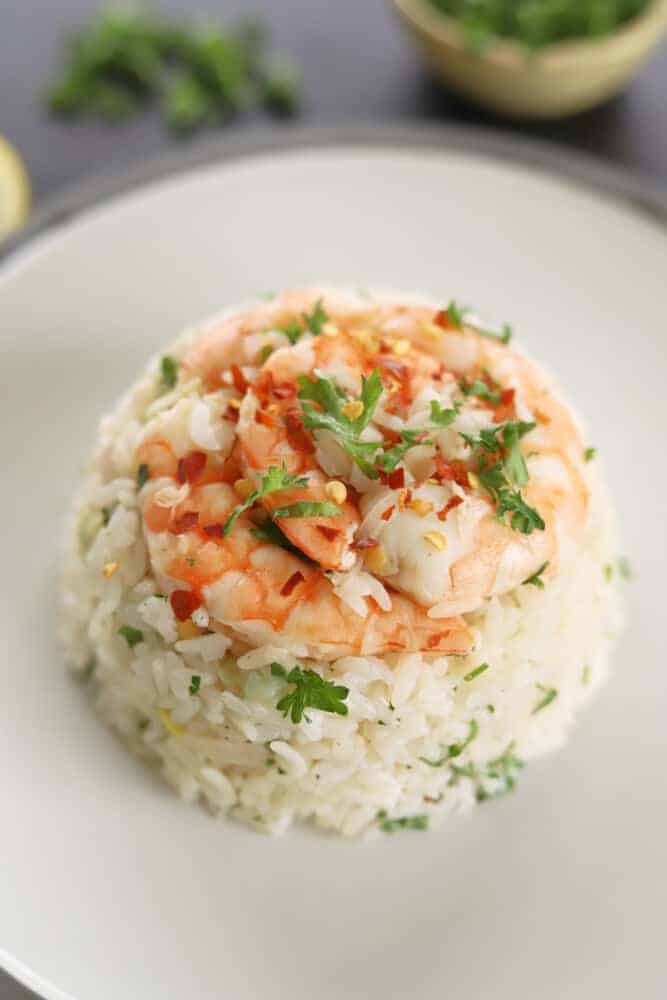 a serving of lemon garlic shrimp and rice on a white plate.