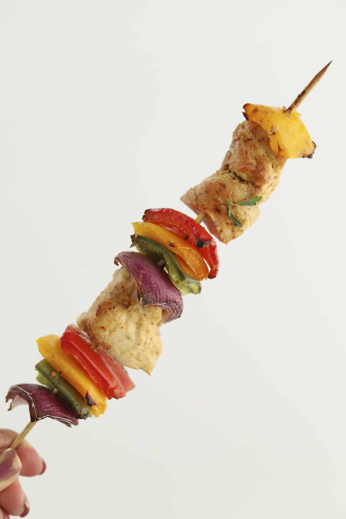 an oven-baked chipotle chicken skewer with green, yellow, and red peppers and red onions