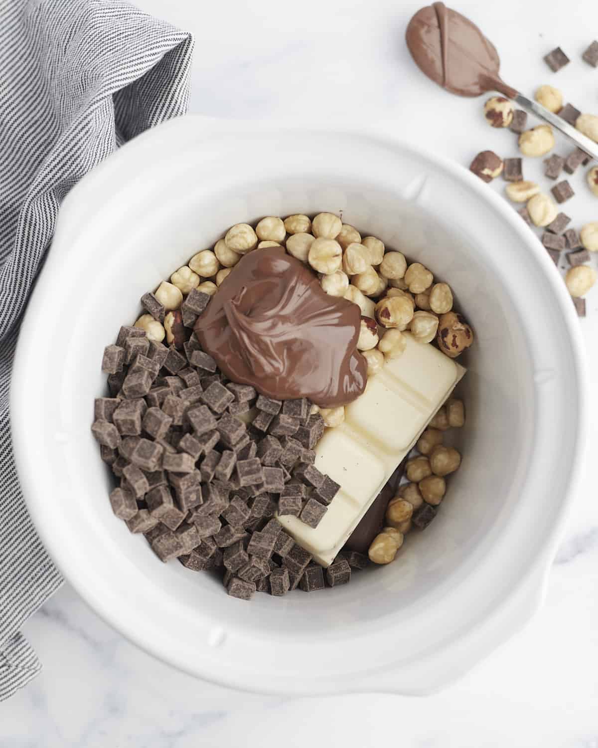 hazelnuts, white chocolate bark, dark chocolate chunks, and nutella in a crockpot