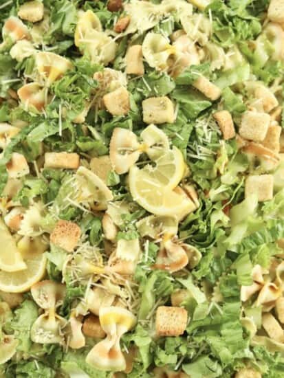 close up image of pesto pasta salad topped with lemon wedges