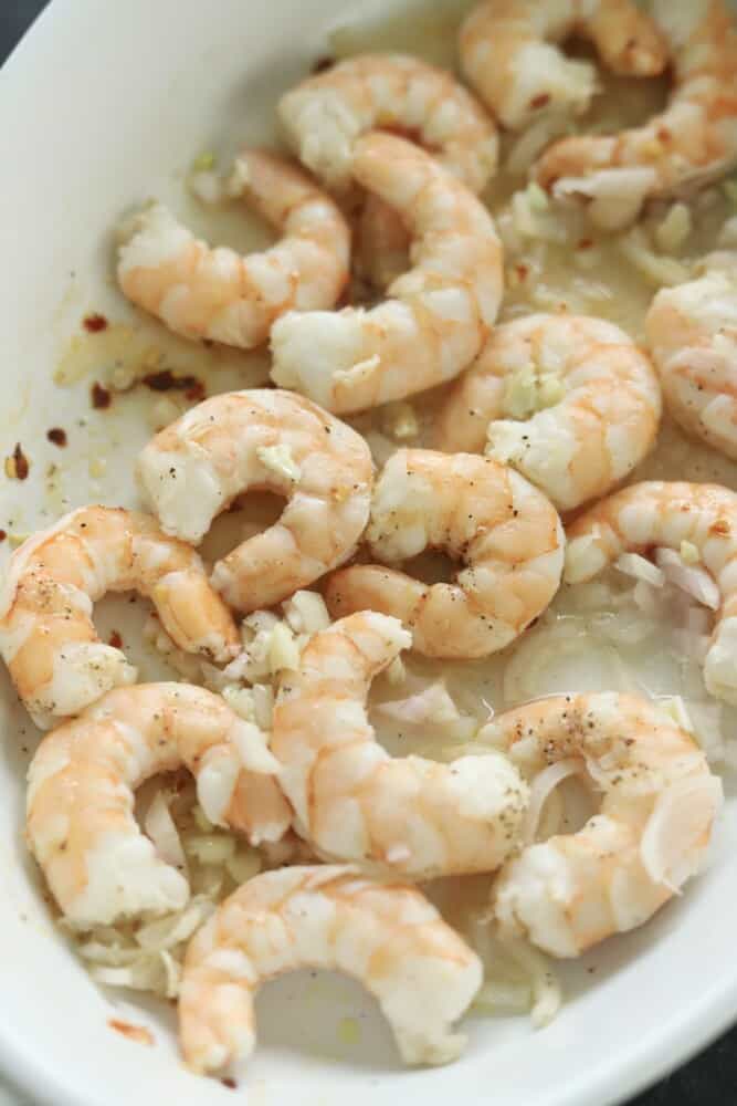 cooked lemon garlic shrimp in a white baking dish.