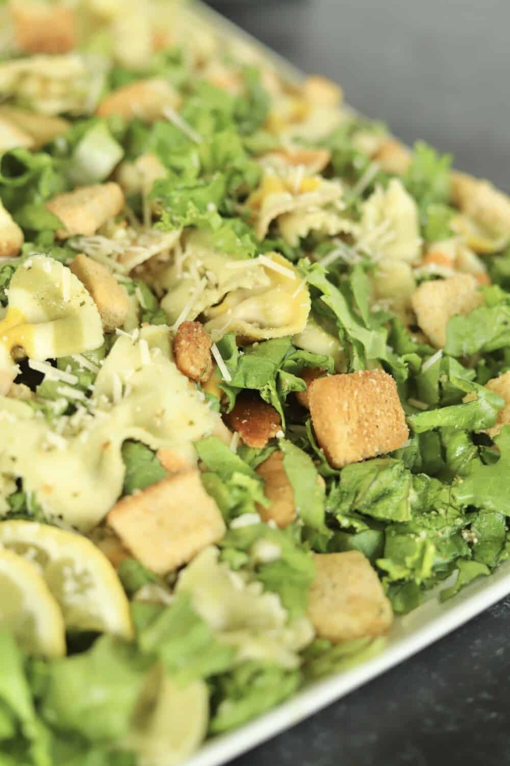 a close up image of a pesto pasta salad recipe on a white platter