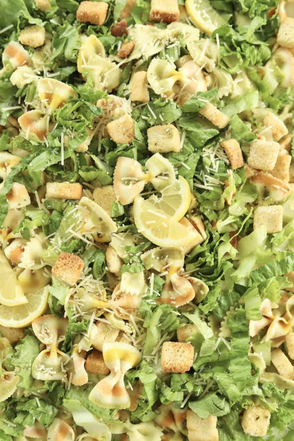 close up image of pesto pasta salad topped with lemon wedges