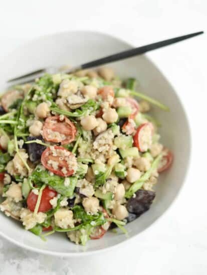 vegan roasted eggplant salad in a white bowl with tahini dressing and quinoa and a chopstick sticking out