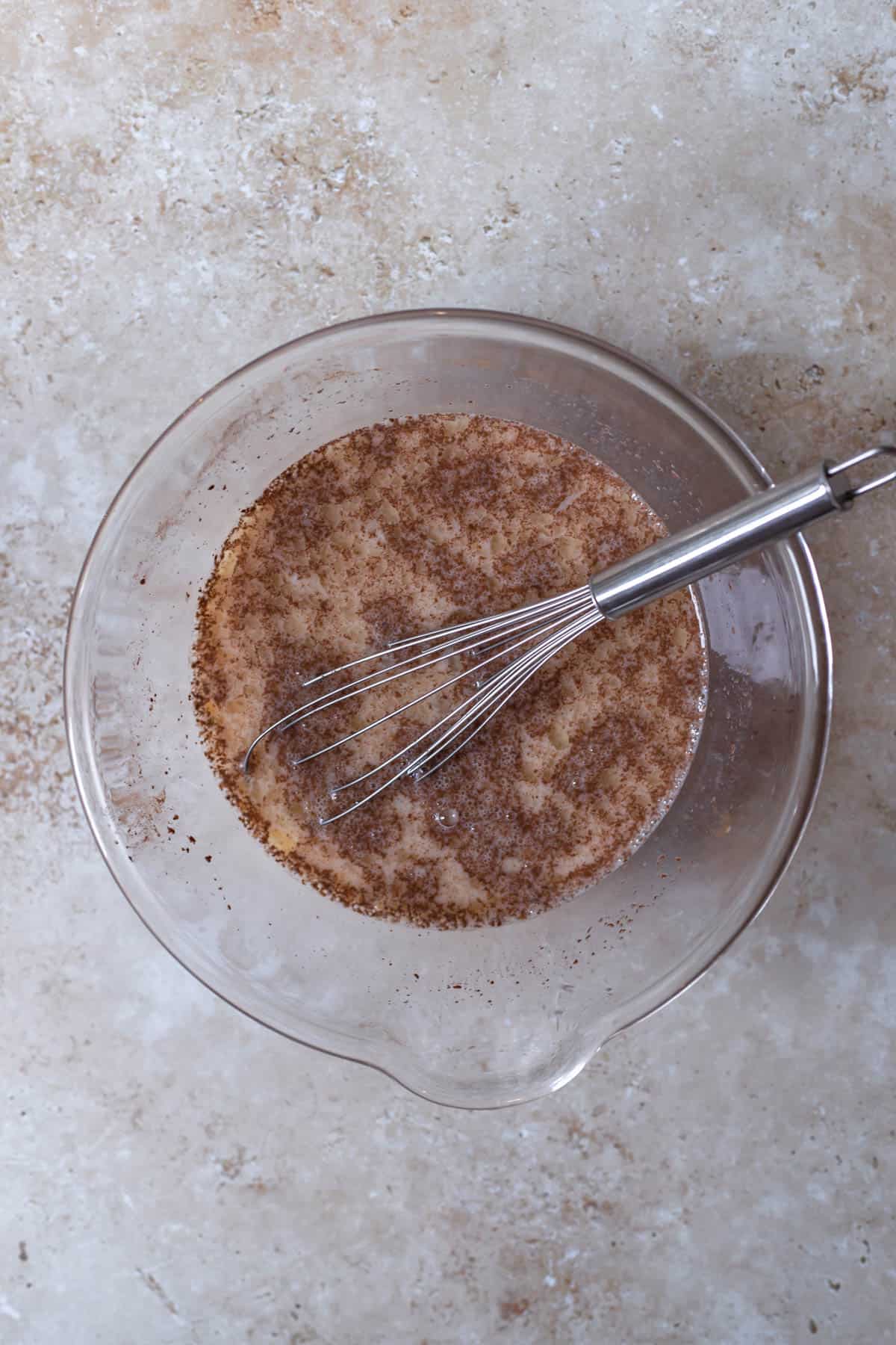 egg mixture in a glass bowl with a whisk sticking out 