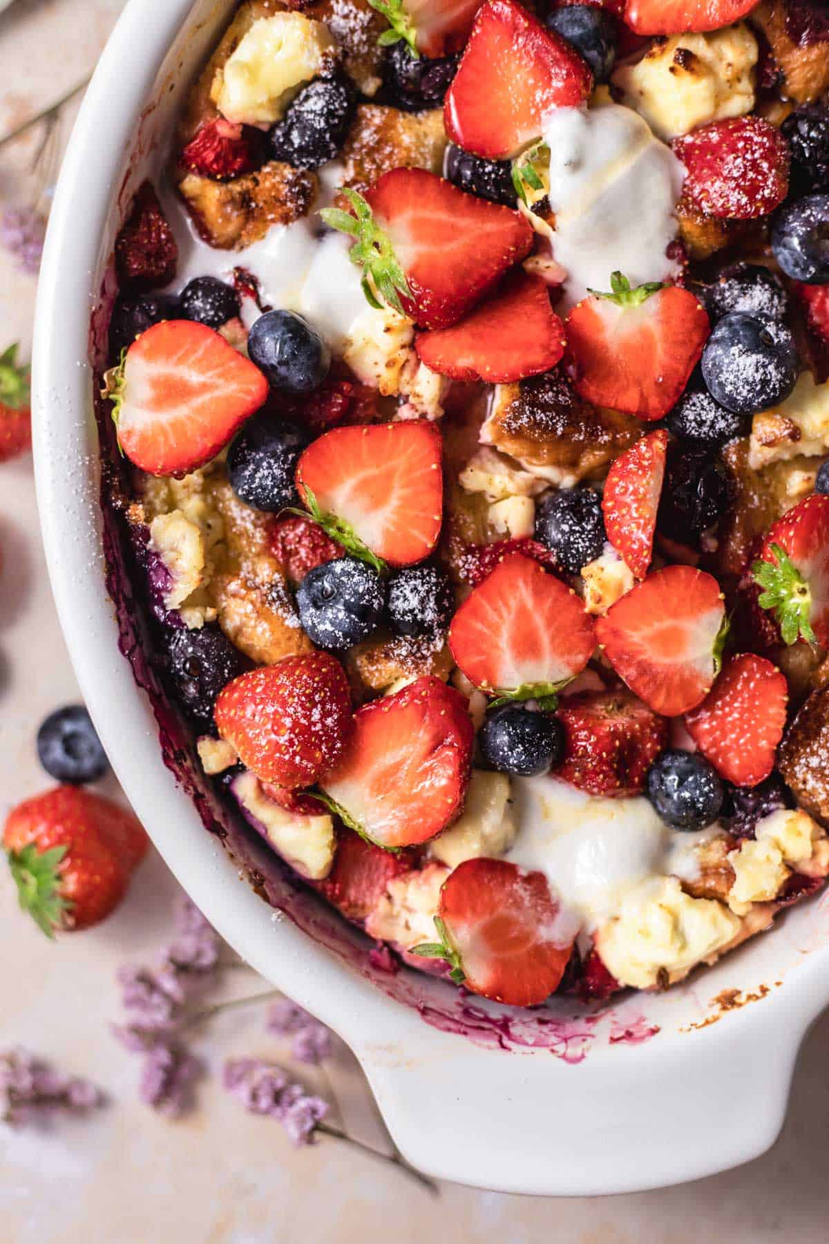 close up image of berry brioche cream cheese french toast in a baking dish