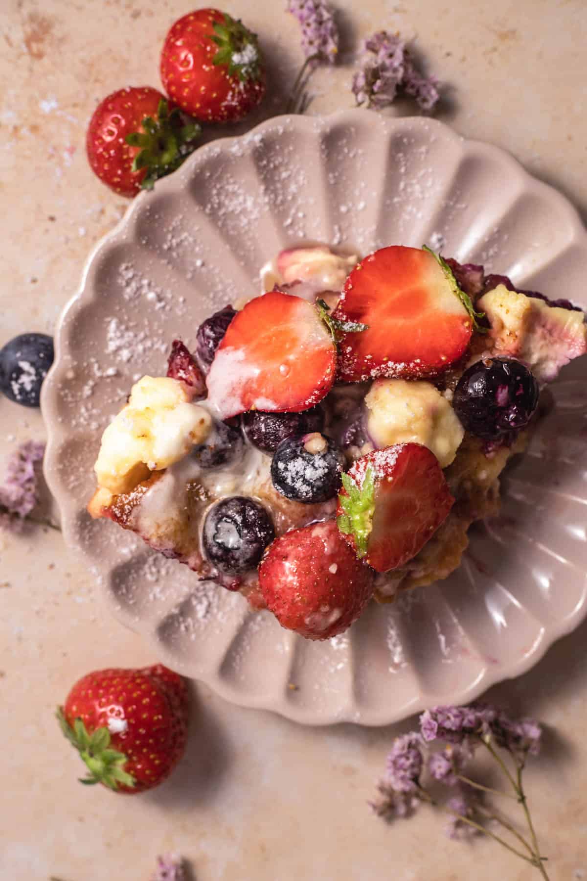 a slice of berry brioche cream cheese french toast on a pink plate