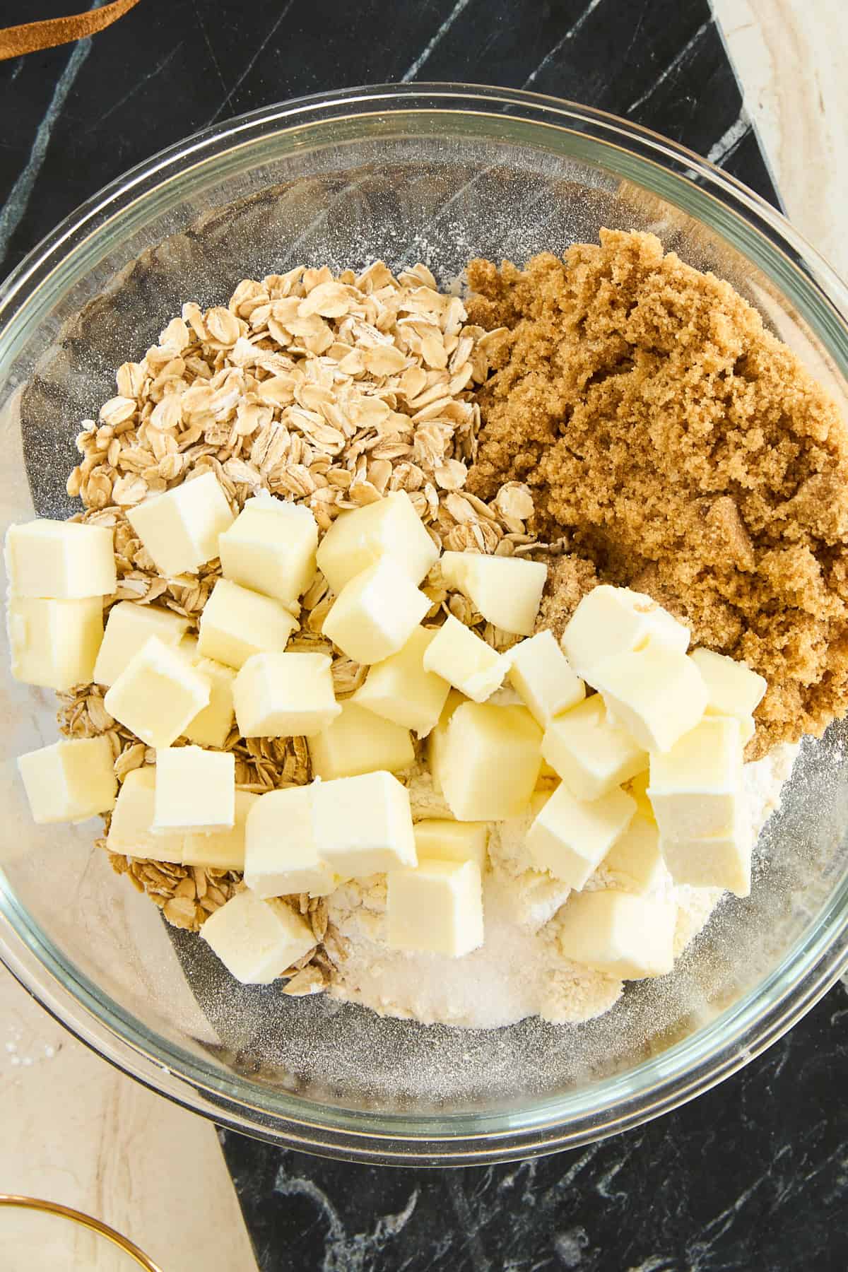 Oats, salt, brown sugar, salt, and cubes of butter in a bowl. 