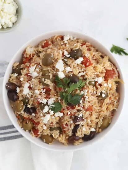 a bowl of Greek rice bake topped with feta and fresh herbs
