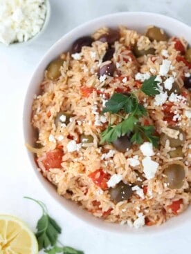 overhead image of a bowl of Greek rice topped with fresh herbs