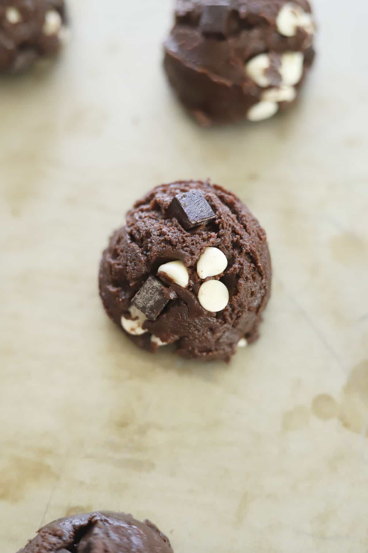 double chocolate chunk cookie dough mound on parchment paper on a baking sheet