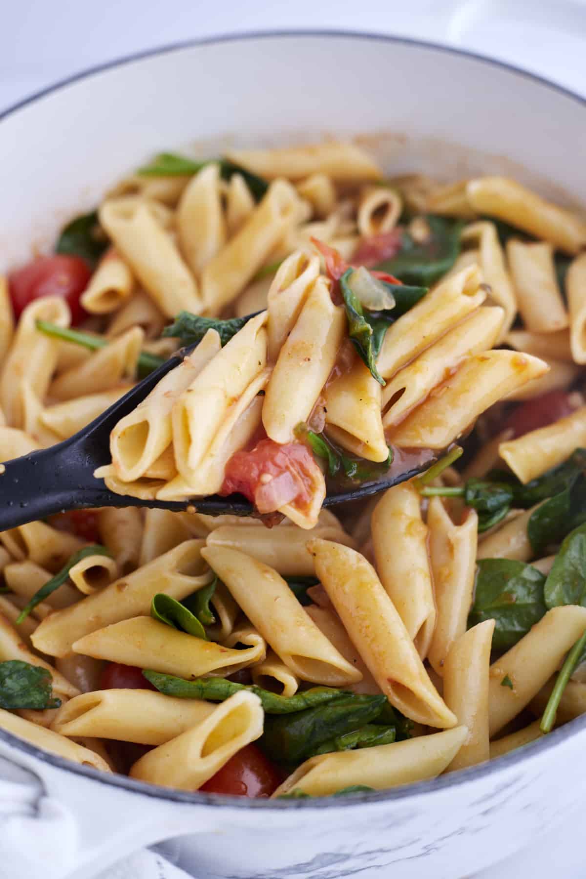 close up pot of tomato and spinach pasta