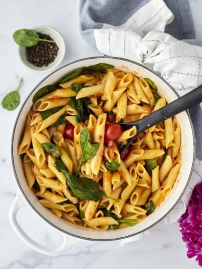 tomato basil one pot pasta in a white dutch oven with a black serving spoon