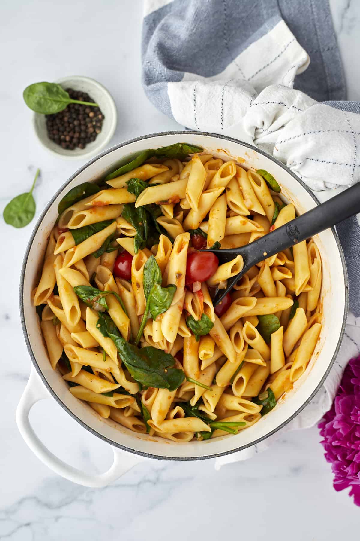 overhead of one pot spinach and tomato pasta with mixing spoon