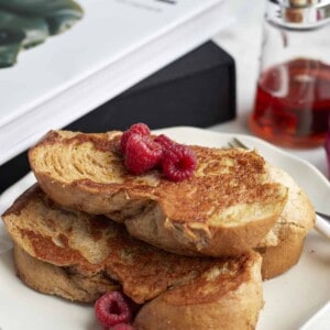 a plate of sheet pan french toast topped with raspberries