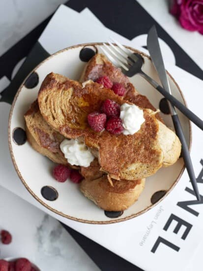 a plate of sheet pan french toast topped with raspberries and whipped cream