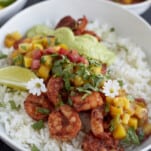 a bowl of blackened shrimp with cilantro lime dressing over rice with mango salsa