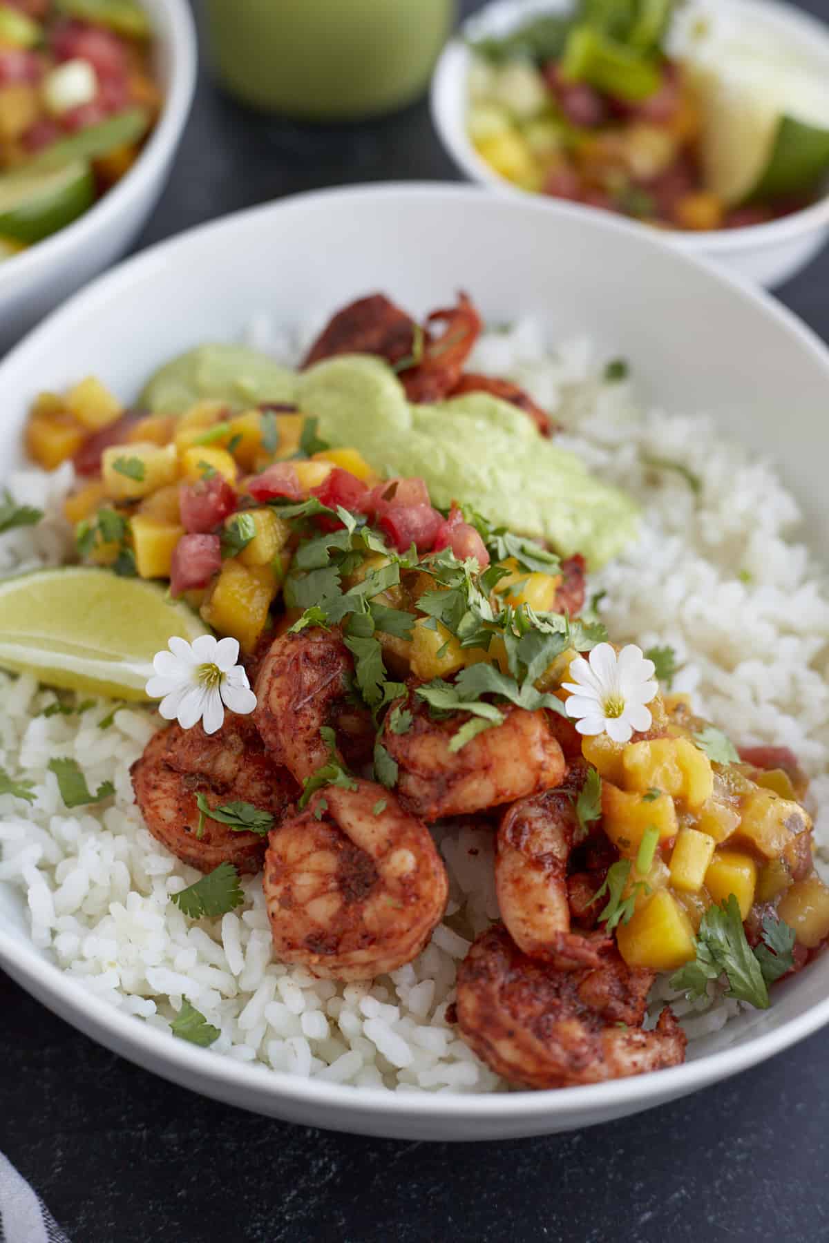 a bowl of blackened shrimp with cilantro lime dressing over rice with mango salsa.