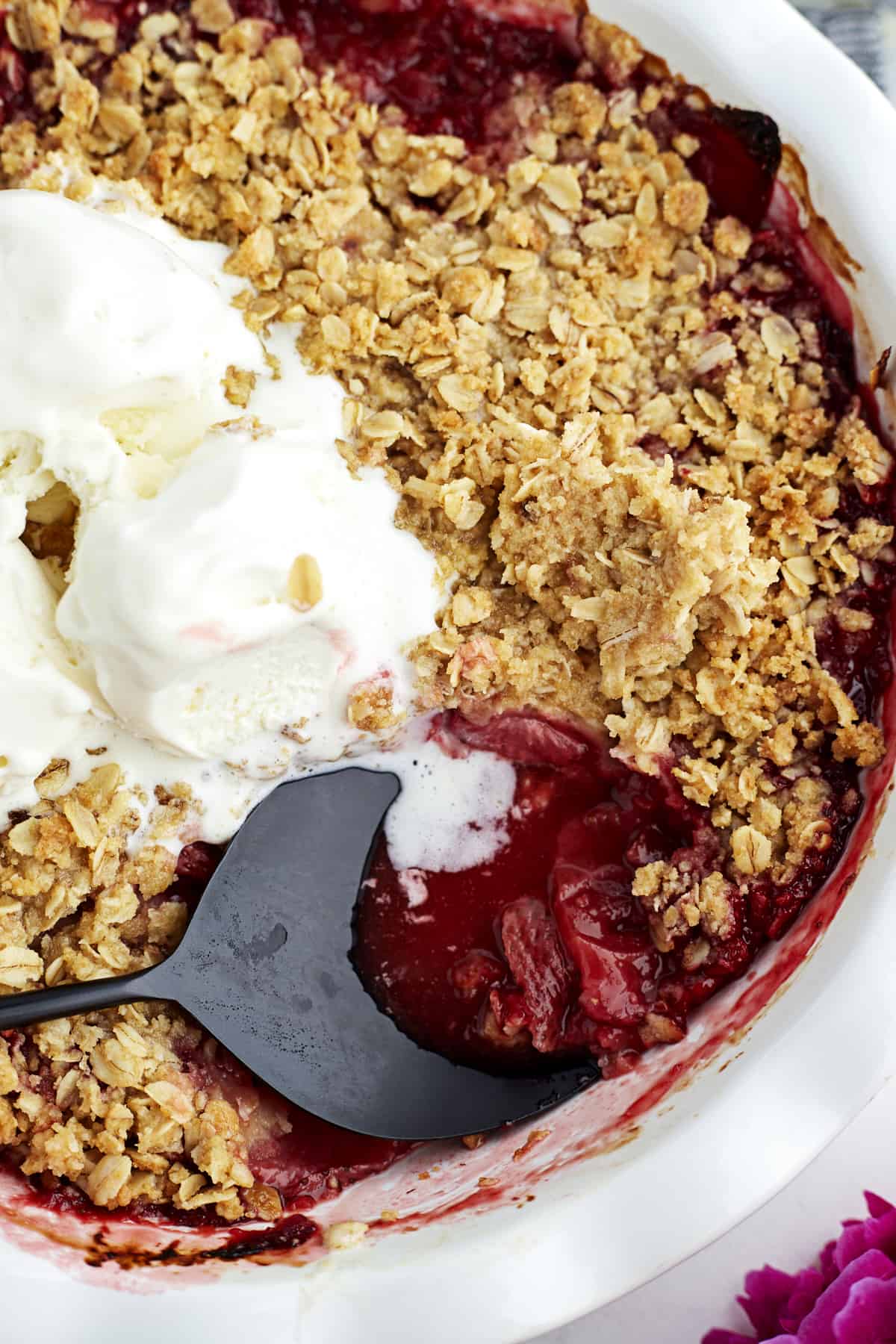closeup Strawberries in pie dish with oat crumble, ice cream, and serving spoon