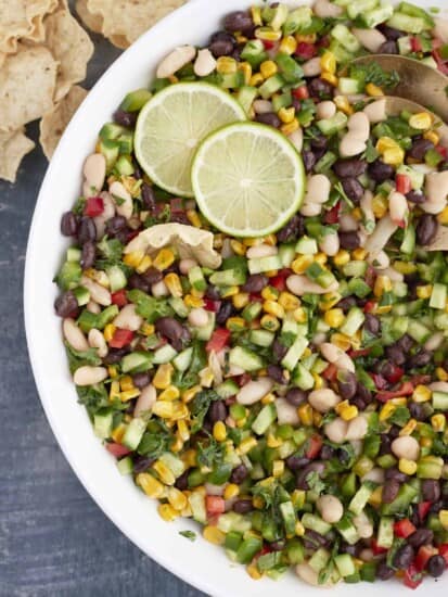 large white bowl with cowboy caviar, limes, and gold spring spoons