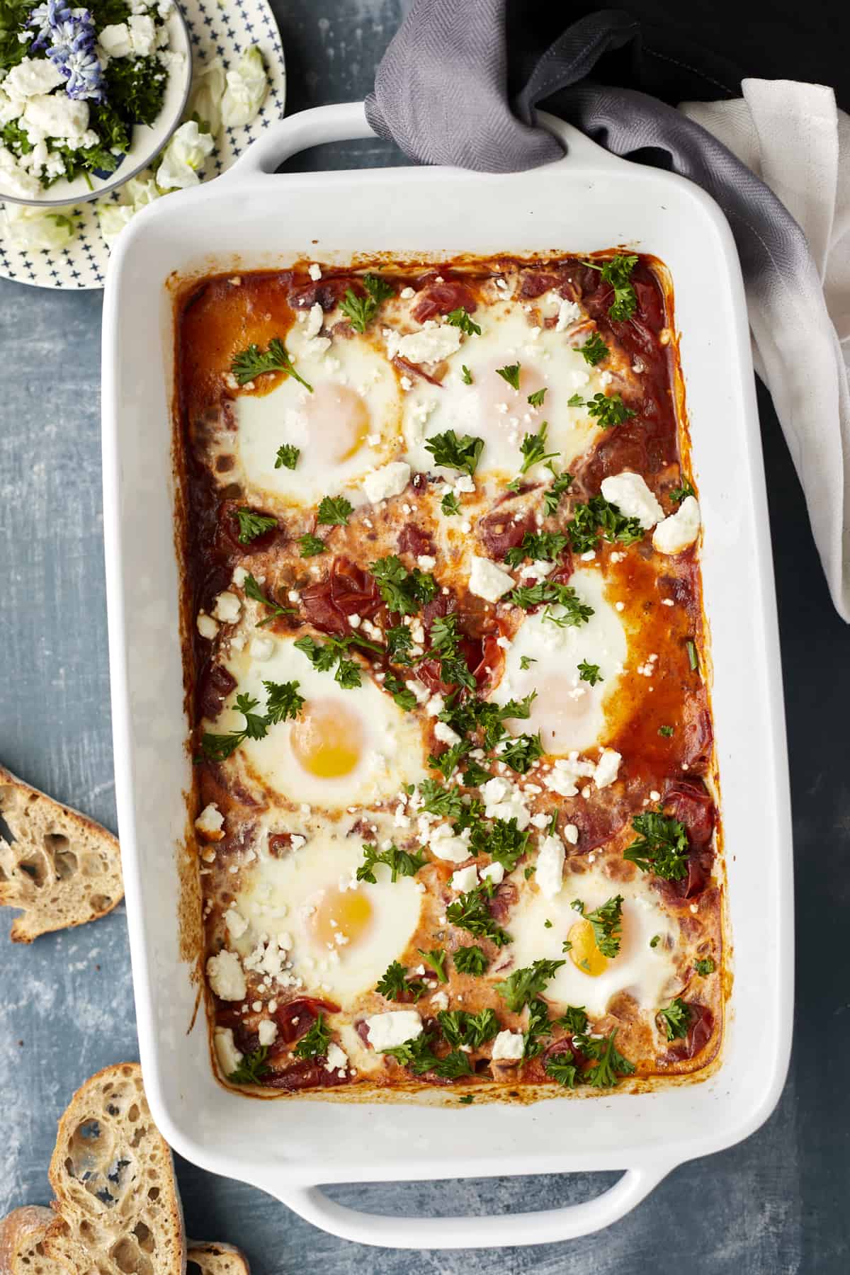 oven baked shakshuka in a baking dish with peices of bread around 