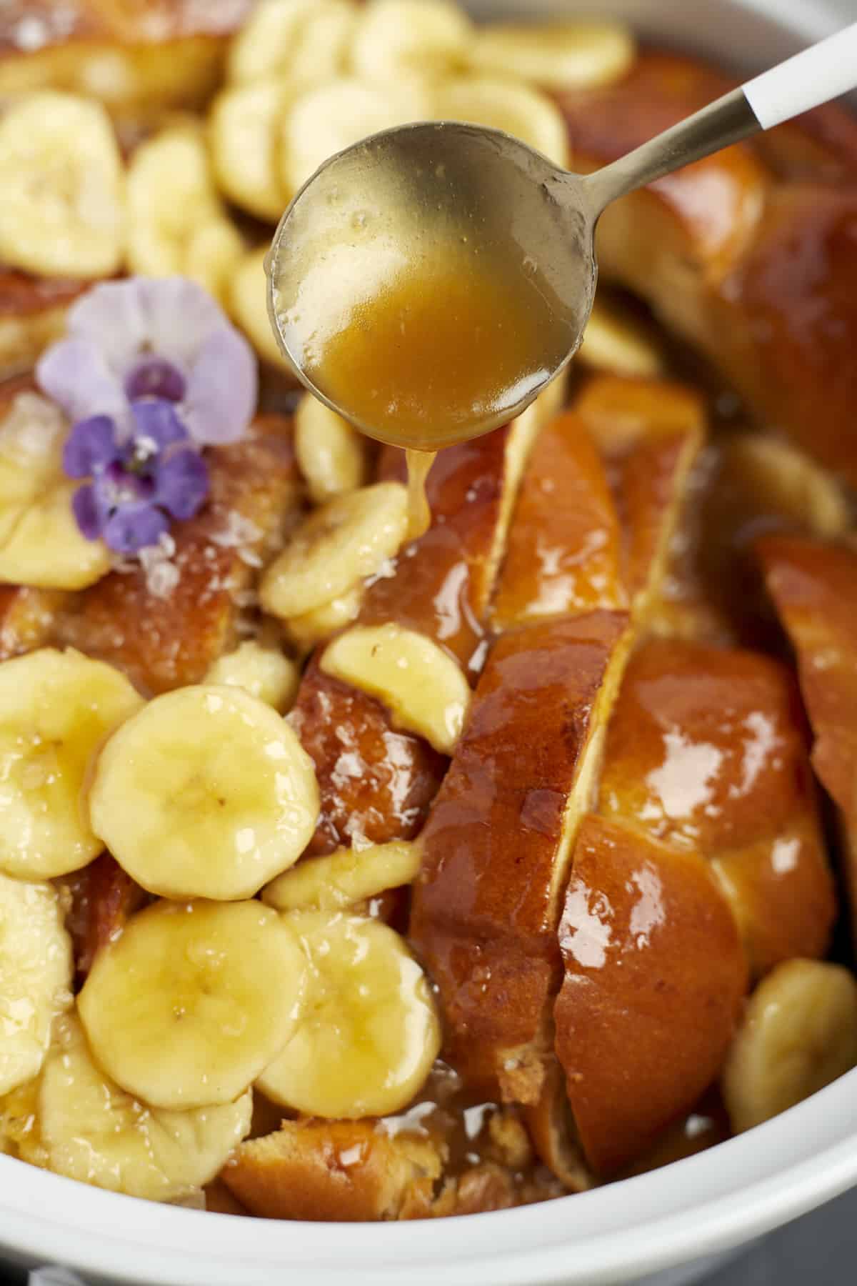 a brown sugar mixture being poured over bananas foster french toast