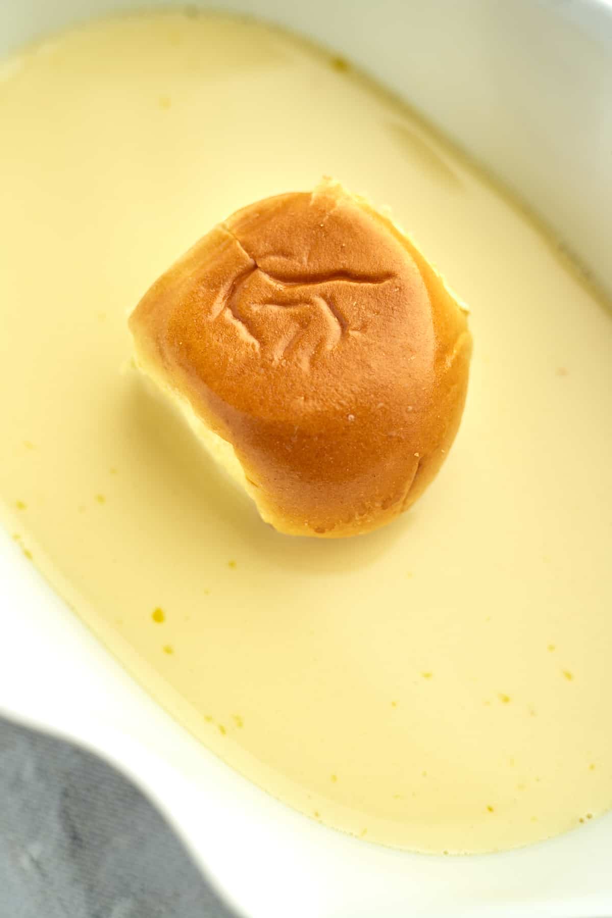 a brioche bun sitting in an egg mixture for french toast