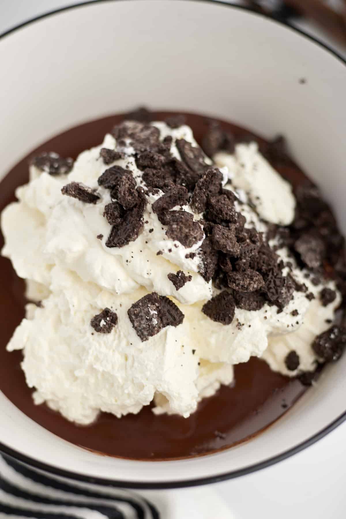 bowl of melted chocolate with whipped cream and oreos