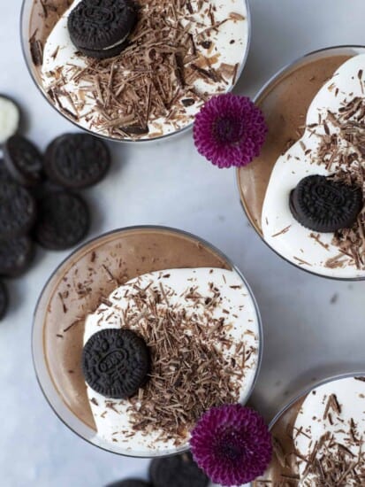 overhead of oreo chocolate mousse in ramekins garnished with whipped cream, chocolate shavings and mini oreo cookies.