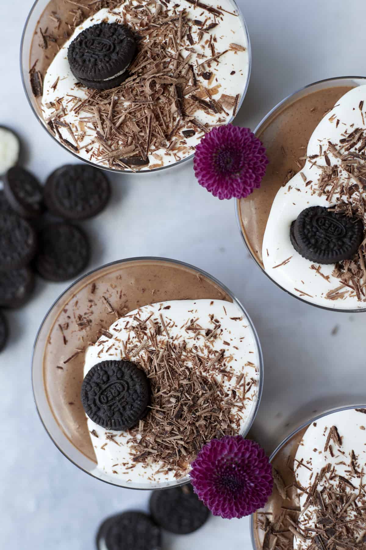 overhead of oreo chocolate mousse in ramekins garnished with whipped cream, chocolate shavings and mini oreo cookies.